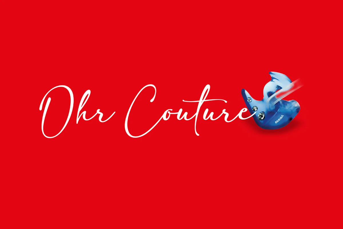 Schriftzug „Ohr Couture“ auf einem rotem Hintergrund mit einer blauen Otoplastik